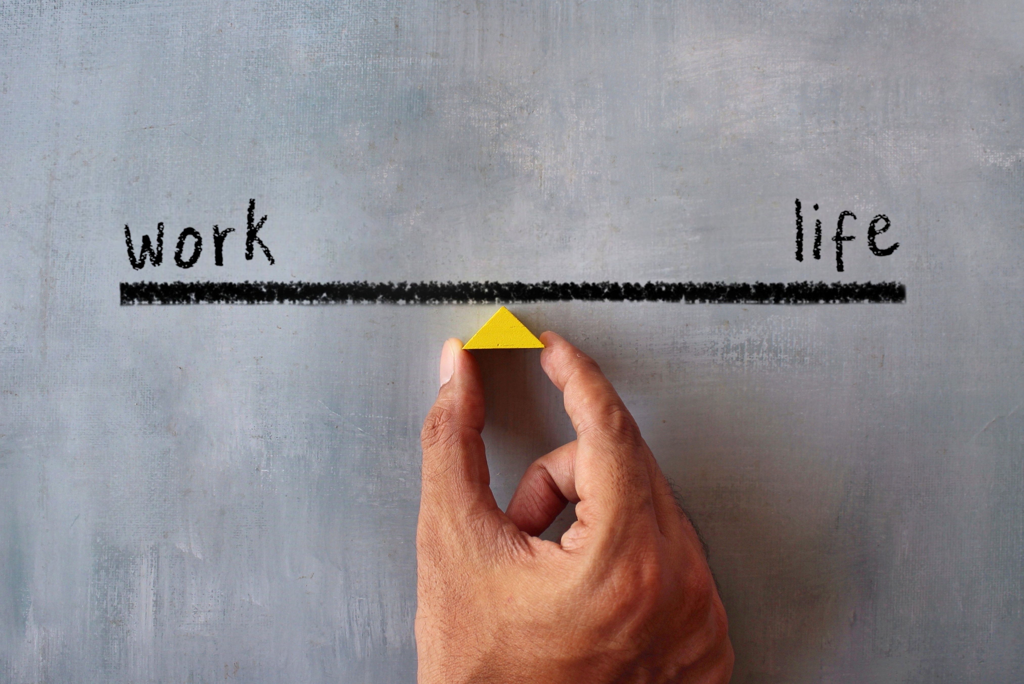 Top view image of hand holding wooden triangle. Work life balance concept.